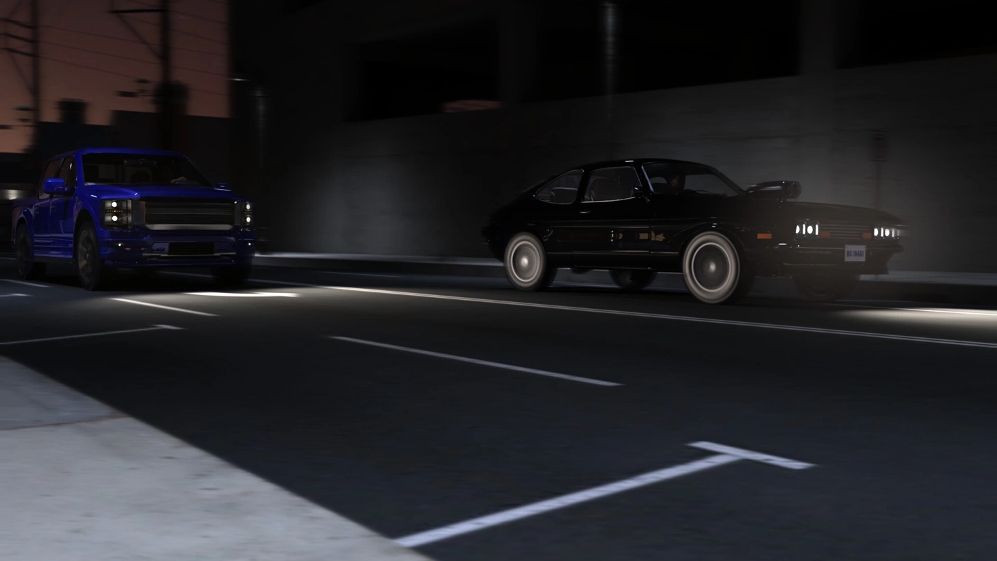 Two sports cars face one another on a dark city road.